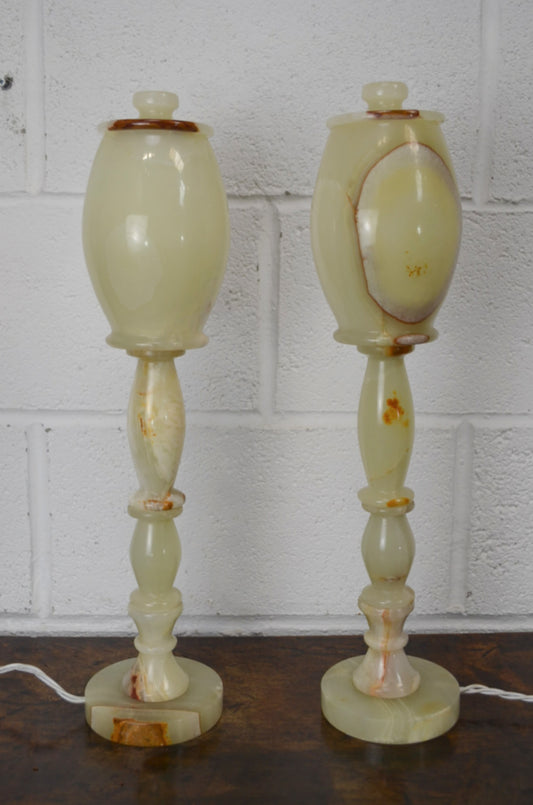 Two onyx table lamps against a white brick wall.