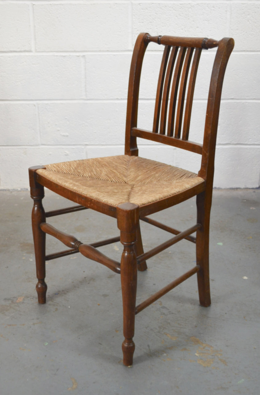 Wooden chair with rush seat against a white wall